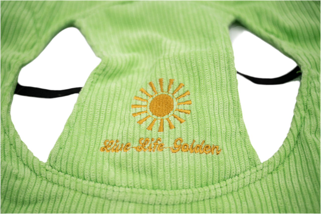 Close-up of light green corduroy dog hat showing embroidered yellow sunburst and “Live Life Golden” text — The Golden Life Key Lime Fisherman collection.