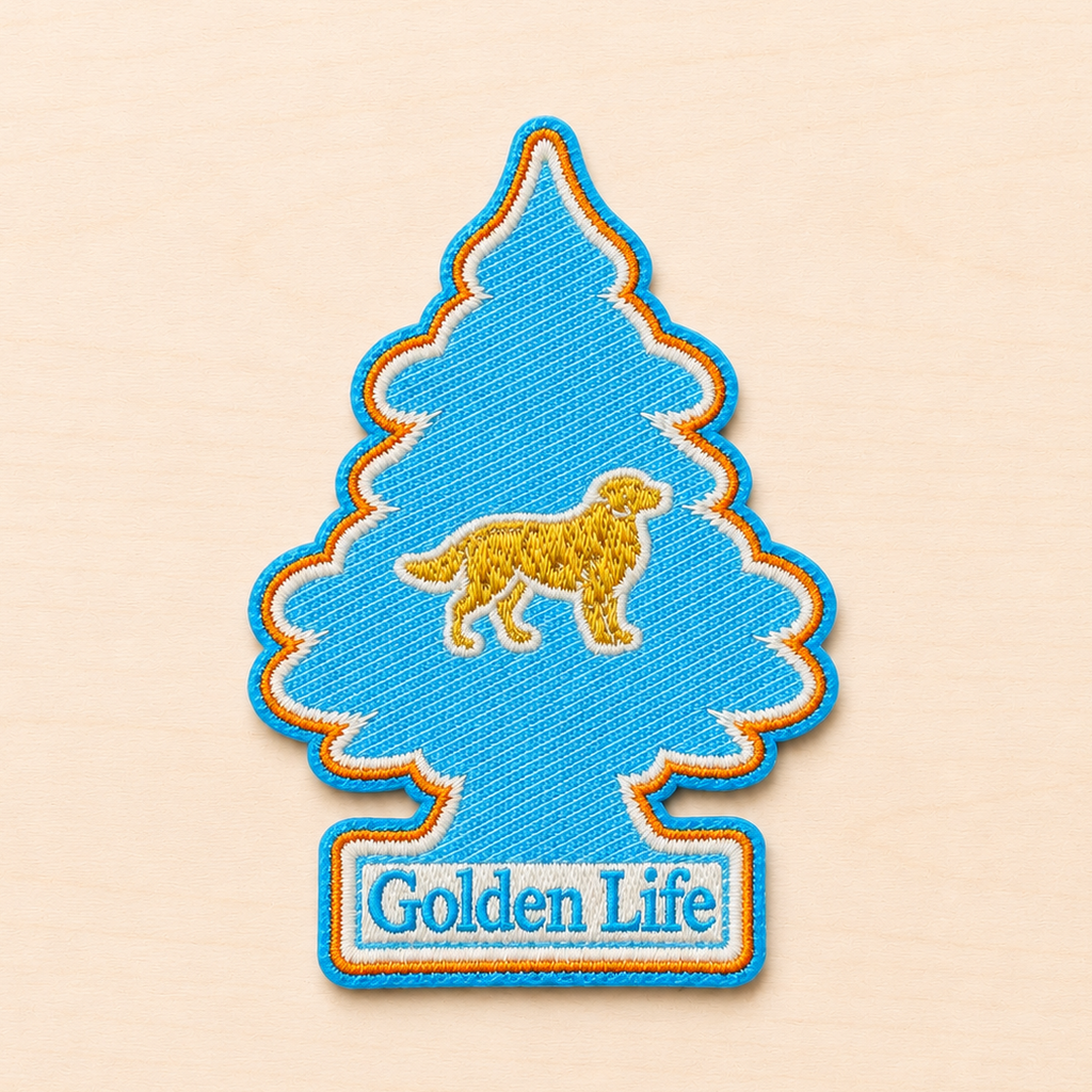 Tree-shaped embroidered patch inspired by a classic air freshener silhouette, featuring a small golden retriever icon above “Golden Life” text in light blue and white embroidery with bright blue and orange borders, displayed on a light wood surface.