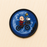 Retro-inspired embroidered patch featuring a cartoon-style child riding a bicycle across a glowing full moon with a dog companion in the front basket, evoking nostalgic 1980s adventure movie vibes.