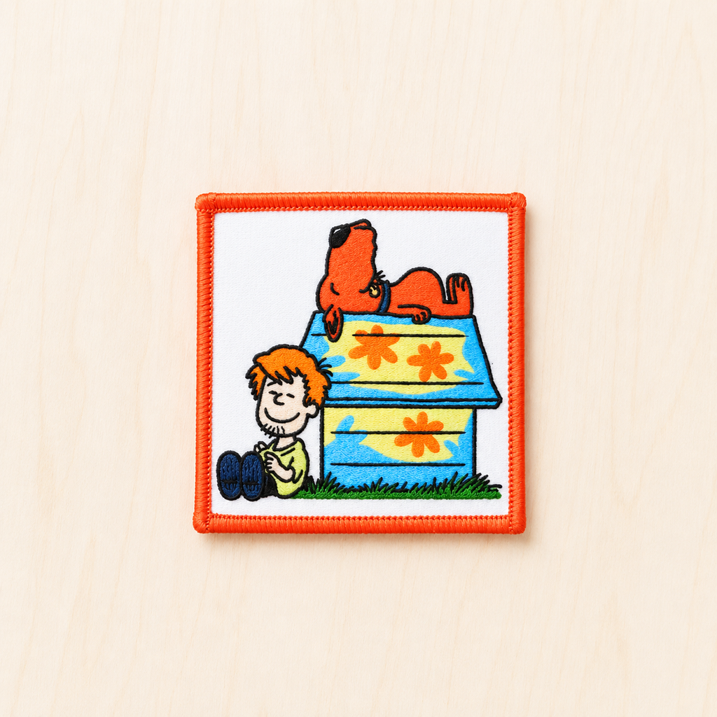 Retro-inspired embroidered patch featuring a cartoon-style child sitting beside a colorful doghouse with a relaxed orange dog lounging on top, evoking nostalgic Saturday morning cartoon vibes.