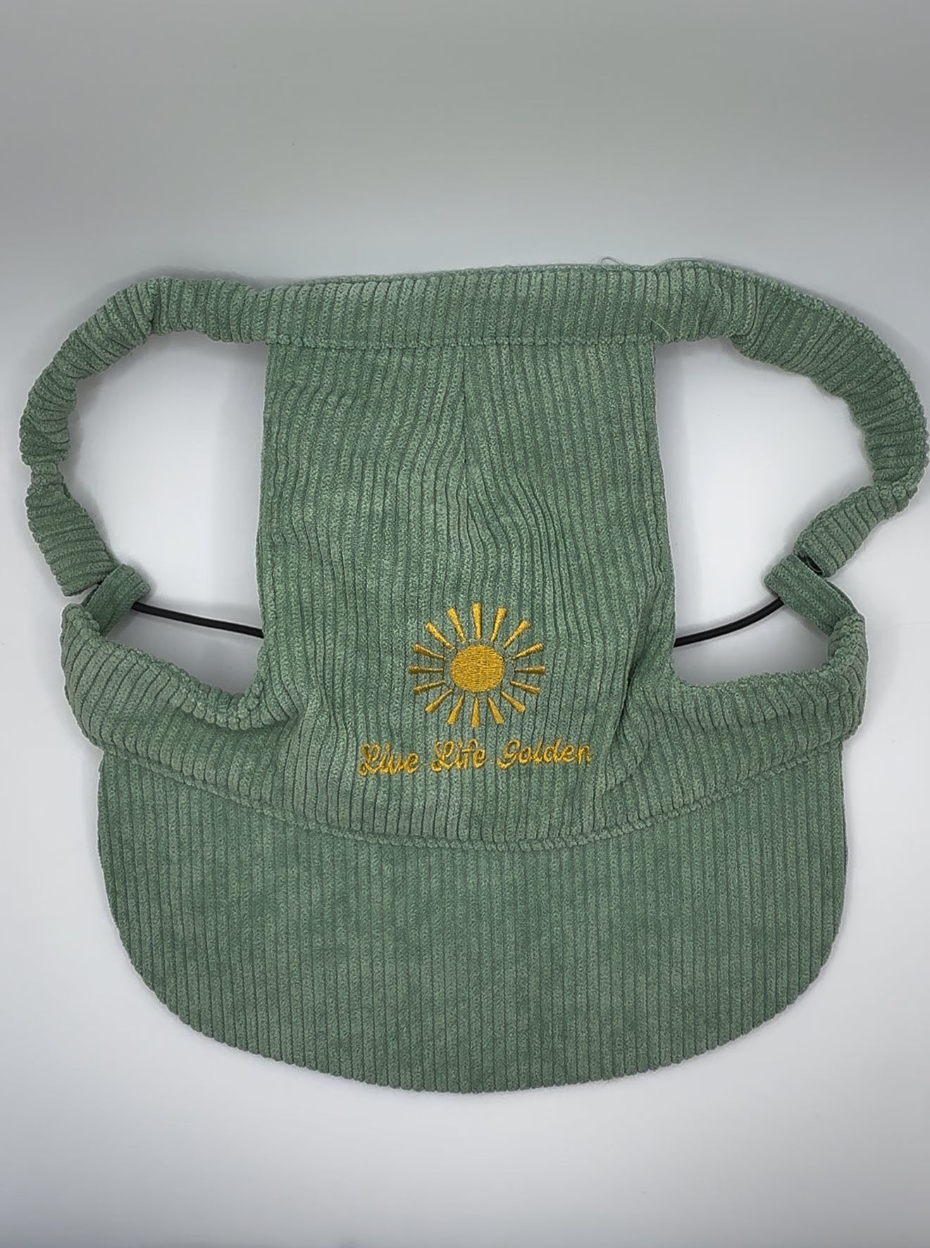 Green corduroy dog hat with ear holes and sun embroidery reading ‘Live Life Golden.’