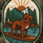 Embroidered adventure iron on patch featuring a golden retriever paddleboarding on calm water with mountains and sunrise in the background.