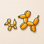 Set of two embroidered orange balloon dog iron-on patches in small and large sizes with black and white stitched borders on a light wood background.