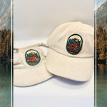 Cream corduroy human and dog hat set featuring the Kodiak adventure paddleboard iron on patch with a golden retriever, mountains, sun, and water.