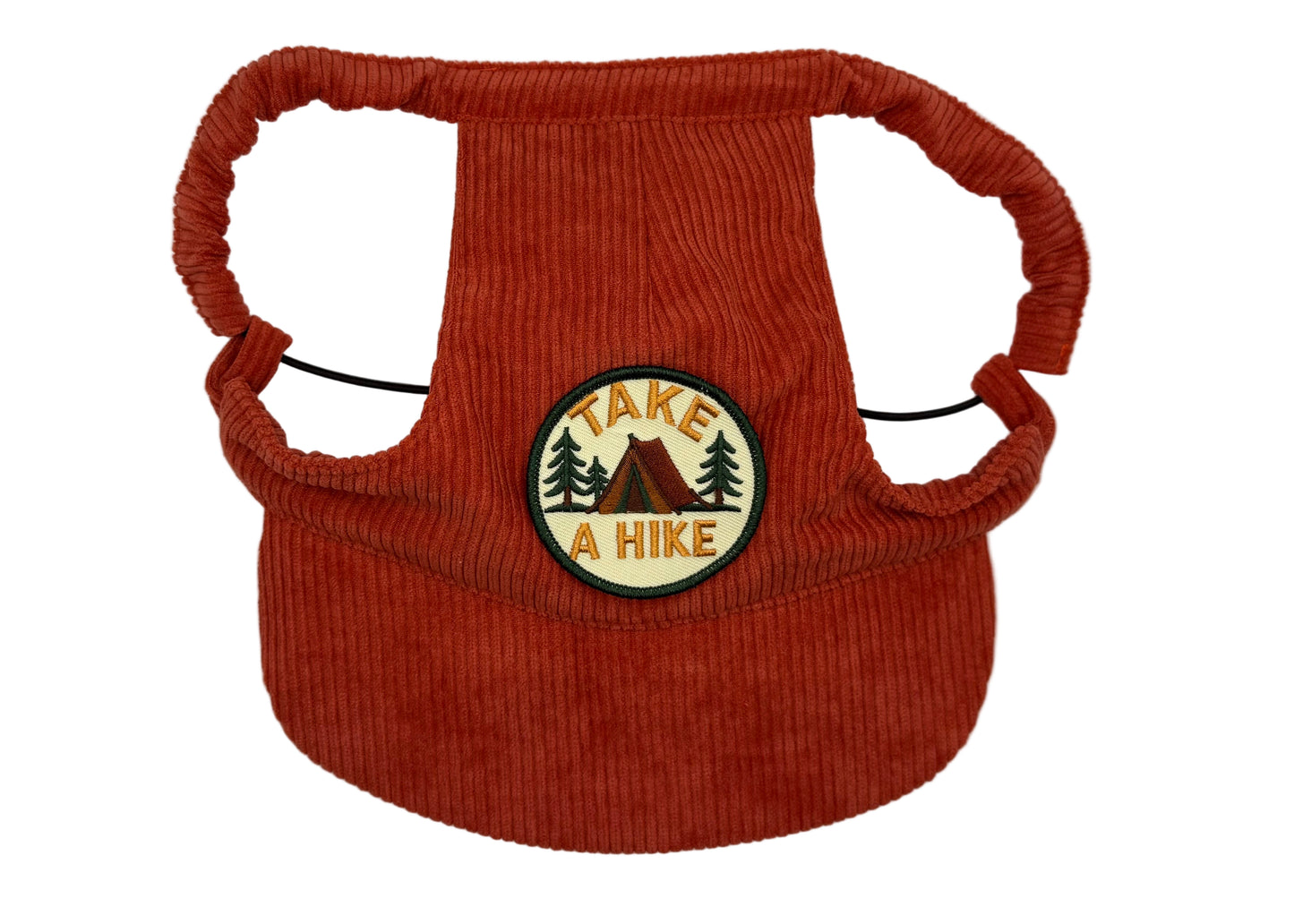 Rust-red corduroy dog hat featuring a “Take a Hike” camping patch with a tent and pine trees — designed with adjustable straps, a curved brim, and soft corduroy texture from The Golden Life Golden Gala collection.