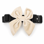 Cream velvet dog bow in sugar cookie color attached to a black dog collar on a white background