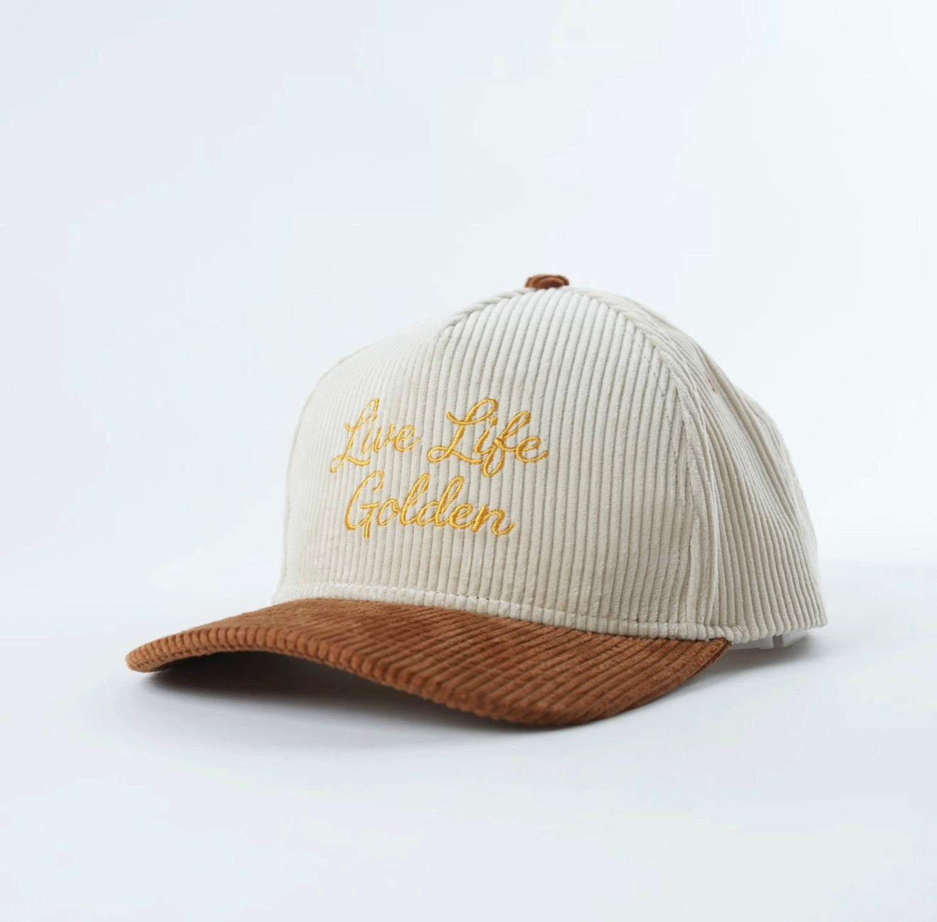 Angled view of embroidered corduroy snapback hat in cream and brown with “Live Life Golden” stitching